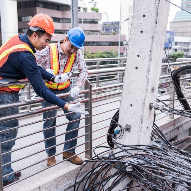 Electric_utilities_two_men_work_city_wires